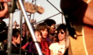 Mick Jagger (in red) and Keith Richards (in shades, natch), just off stage at the Altamont concert, hours before their segment turned deadly. Dec. 6, 1969. Home video footage. National Audio-Visual Conservation Center.